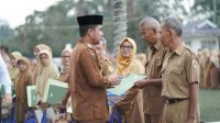 Wali Kota Solok Ramadhani Kirana Putra menyerahkan hadiah ibadah umrah kepada Sarmijan sebagai apresiasi atas pengabdiannya selama 41 tahun di lingkungan Disdukcapil Kota Solok.