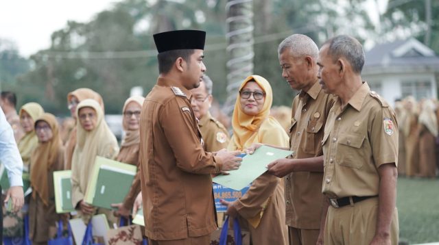 Wali Kota Solok Ramadhani Kirana Putra menyerahkan hadiah ibadah umrah kepada Sarmijan sebagai apresiasi atas pengabdiannya selama 41 tahun di lingkungan Disdukcapil Kota Solok.